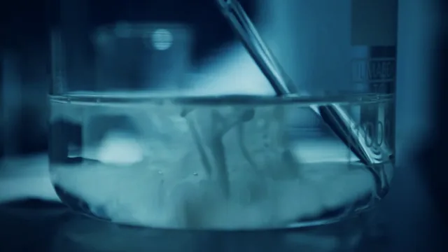 A glass beaker with a stirring rod in cold blue light