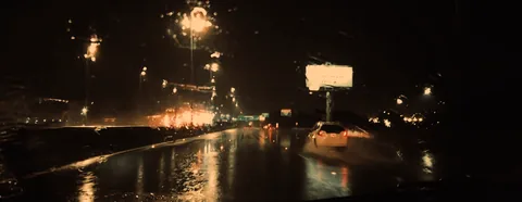 A wet, empty avenue under street lights